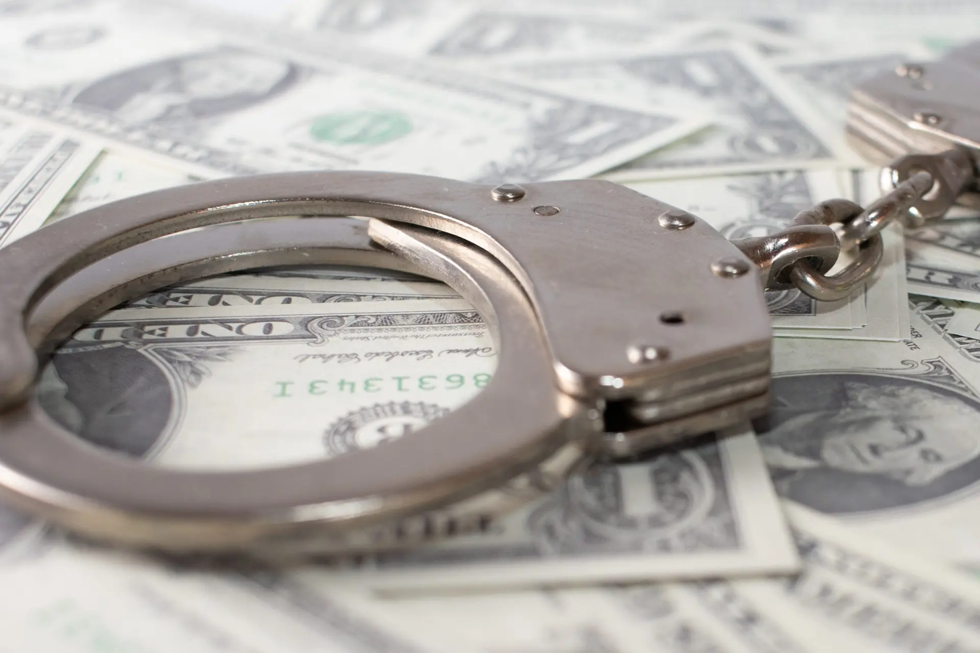 closeup-view-metal-handcuffs-dollars-scaled